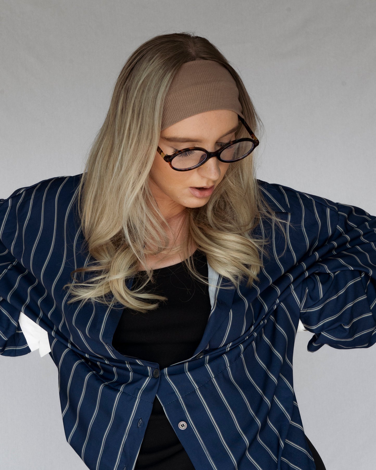 Person wearing a blue striped blazer over a black top against a plain background