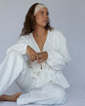 Woman wearing a white outfit sitting on a plain background