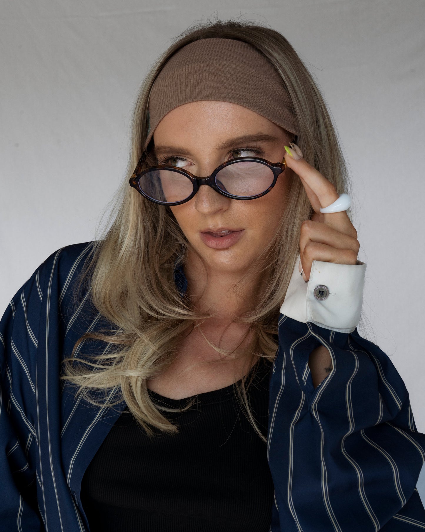 Woman wearing a brown headband and black sunglasses with a white background
